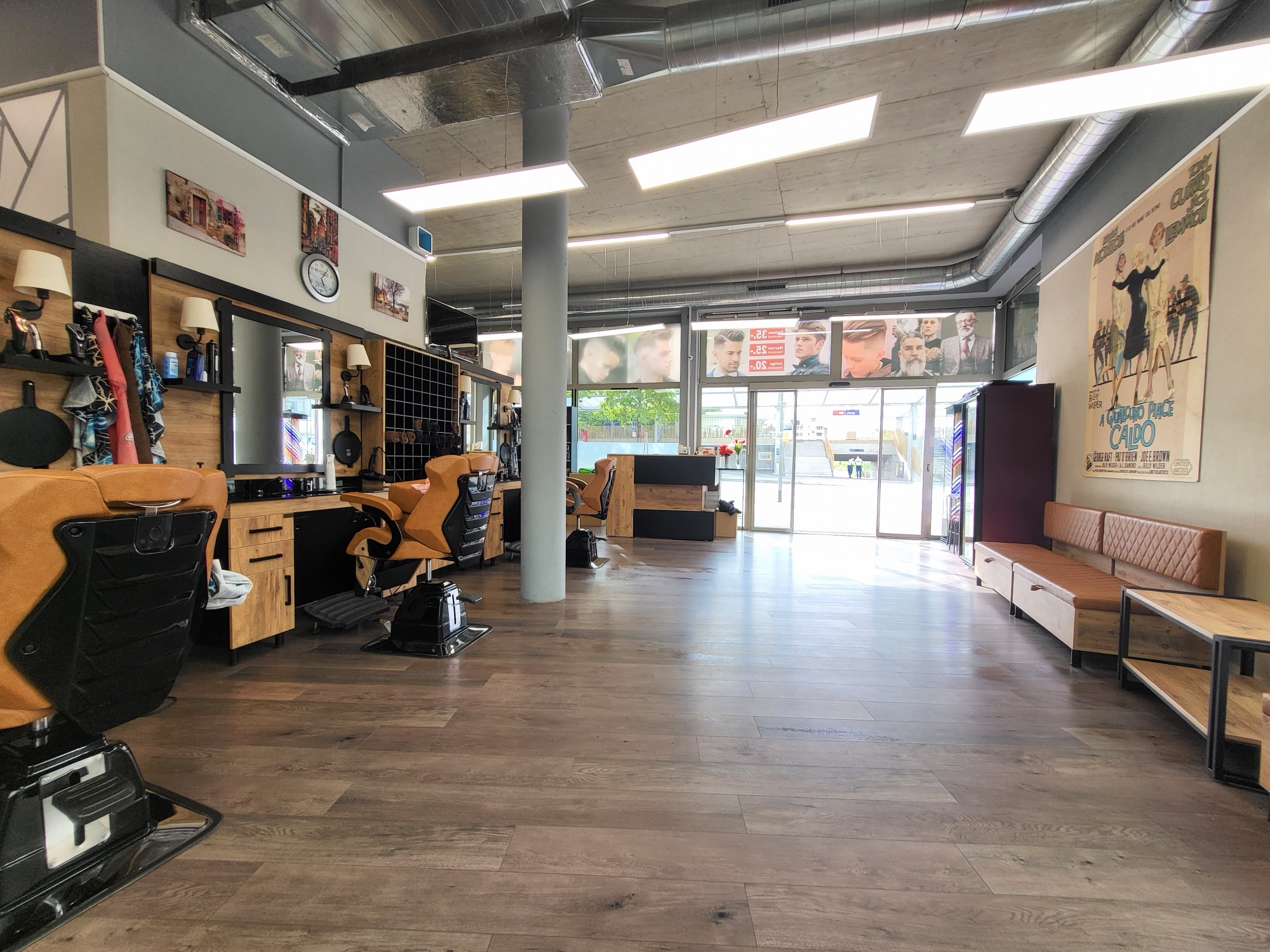 Blick durch den Salon: Arbeitsplätze mit Spiegeln, Ledersitzbank und Fensterfront
